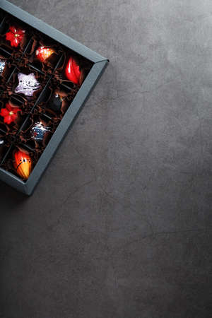A set of colorful exclusive handmade chocolates in a box on a black background. Full screen view from aboveの写真素材