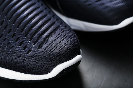 Running shoes with mesh and black and white soles close-up on a dark background. Top view of sports...