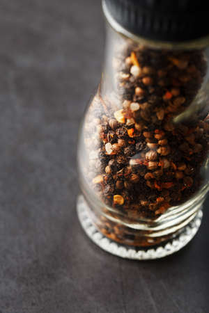 A mixture of peppercorns seasoning and salt in a transparent mill close-up. Macroの写真素材