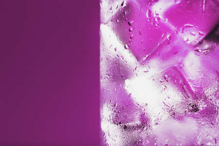 Ice cubes in a glass with refreshing ice water on a pink background. close-upの写真素材