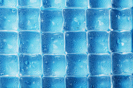 Ice made of cubes lined up with drops on a blue backgroundの写真素材