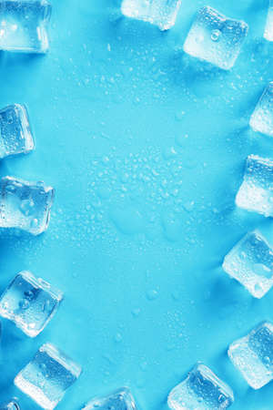 Ice cubes with water drops scattered on a blue background, top viewの写真素材