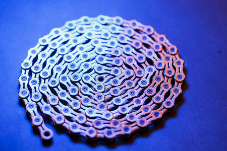 Patterns of a technological bicycle chain braided in a circle with blue-purple illuminationの写真素材