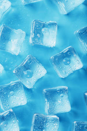 Ice cubes with water drops scattered on a blue background, top viewの写真素材