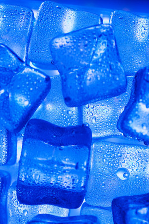 Ice made of cubes lined up with drops on a blue background