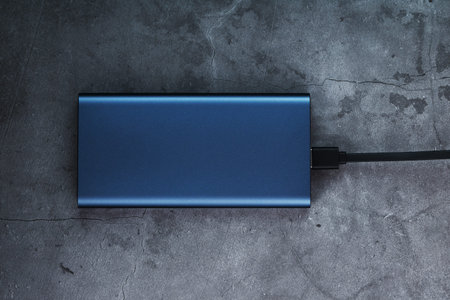 Portable External Battery Power Bank blue with USB Cord on a dark textured background for charging...