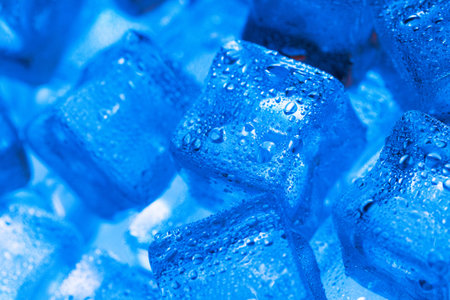 Ice made of cubes lined up with drops on a blue background