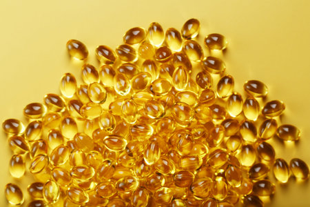 The texture of the capsules in the shell with liquid vitamin D3 in full screen. Gold capsules with a...