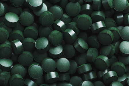 Dark Green round tablets of organic spirulina as a texture background in full screen