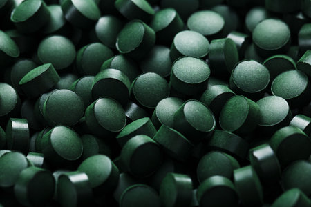 Dark Green round tablets of organic spirulina as a texture background in full screenの写真素材