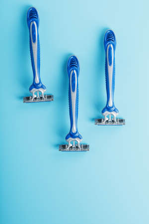 Three shaving machines on a blue background with free space, top viewの写真素材
