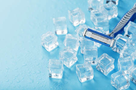 Shaving machine on a blue background with ice cubes. The concept of cleanliness and frosty freshnessの写真素材