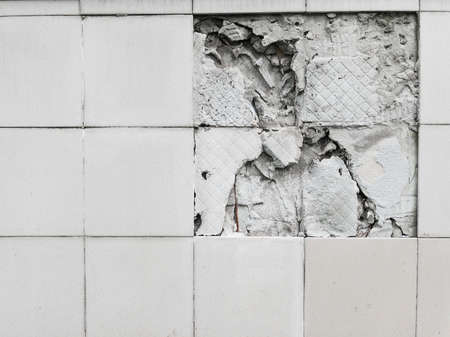 A wall with a broken off gray tile from the wallの写真素材
