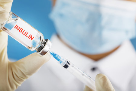 Diabetes treatment a bottle of insulin and a syringe with a needle in the hands of a doctorの写真素材