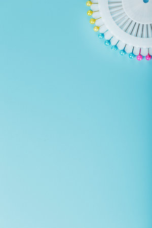 A set of multicolored needles pins in a round platform on a blue background with free space