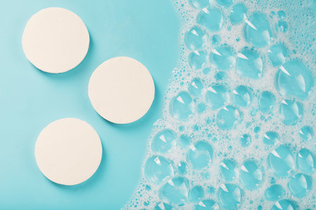 Three bars of round soap with foam on a blue backgroundの写真素材