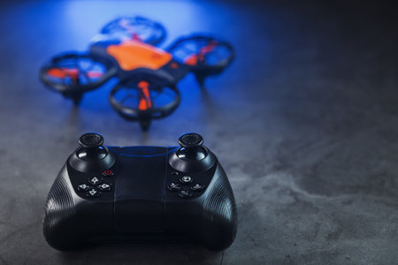 Gaming orange mini drone on a dark background with a joystick controlの写真素材