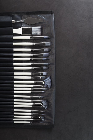 A set of art brushes for drawing on a black background, top view with free spaceの写真素材