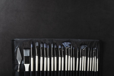 Art tools in a pencil case on a black background, top view with free spaceの写真素材