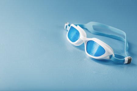 White swimming glasses with a blue lens on a blue backgroundの写真素材