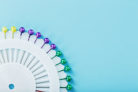 Sewing mother-of-pearl pins in a round white package on a blue background with free spaceの写真素材