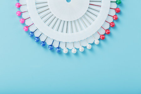 Sewing mother-of-pearl pins in a round white package on a blue background with free spaceの写真素材