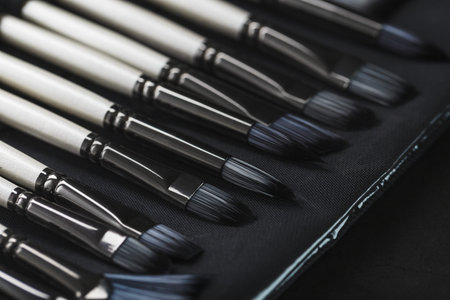 Paint tubes, brushes for painting and palette knifes on old wooden background