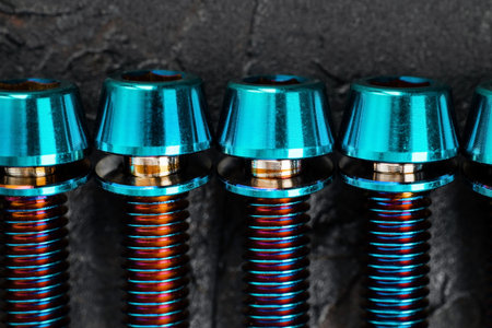 Titanium bicycle bolts on a black textured background close-upの写真素材