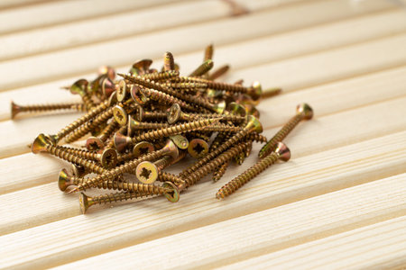 A pile of screws on a table made of wooden slats with warm lighting and free space