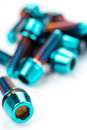 Sturdy titanium hex bolts are positioned on a snow-white background, close-upの写真素材