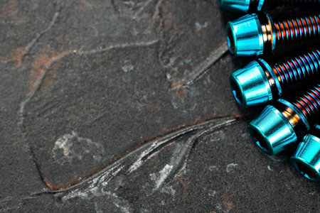 A row of blue Titanium bicycle screws on a black textured background with free spaceの写真素材