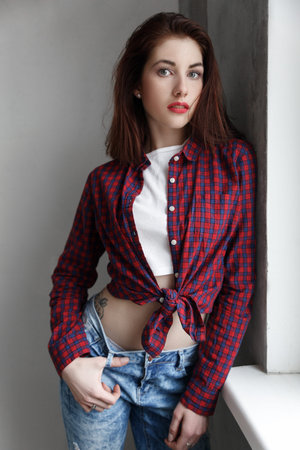 Pretty pin-up girl by the wall in jeans and shirt. Beauty, fashion.の写真素材