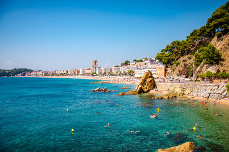 panoramic view of seashore with rock cliff and a town on background in Lloret de Mar, Catalonia,...