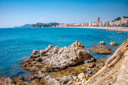 panoramic view of seashore with rock cliff and a town on background in Lloret de Mar, Catalonia, Costa Brava, Spainの写真素材