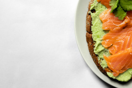 sandwich with guacamole and salmon on a plate on a white backgroundの写真素材