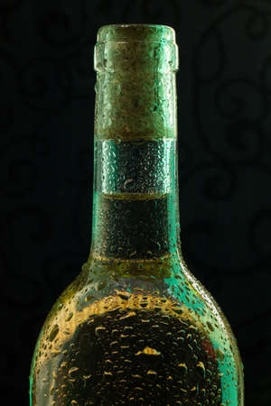 White wine bottle with drops and green highlight on black backgroundの写真素材