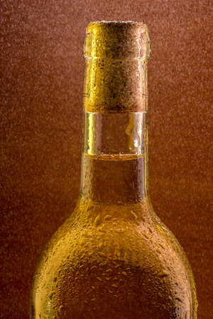 Bottle of white wine with the water droplets on the surface of a wooden background under fine spray の写真素材