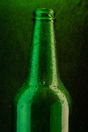 Cold beer bottle with drops on green under spray close-upの写真素材