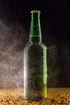 Cold green beer bottle on black with water dropsの写真素材