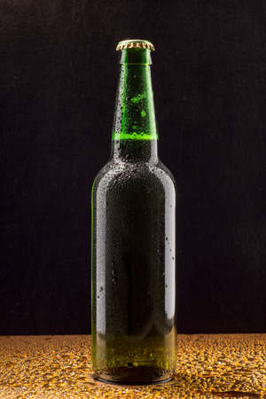 Cold green beer bottle on black with water dropsの写真素材