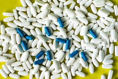 blue and white pills capsule on yellow backgroundの写真素材