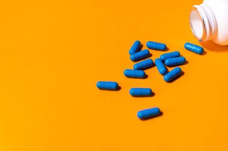 blue pills on orange abstract backgroundの写真素材