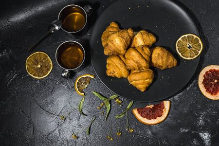 cup of healthy lemon tea with croissants and citrusesの写真素材