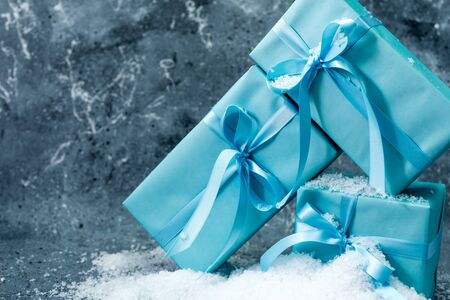 color christmas gift with ribbon and bow in snowの写真素材