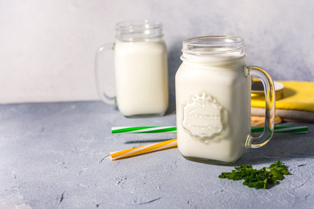 simple homemade kefir in a glass with spices and herbs on a gray background, copy space. Probiotic...