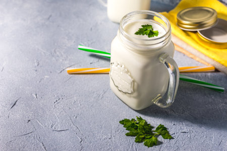simple homemade kefir in a glass with spices and herbs on a gray background, copy space. Probiotic...
