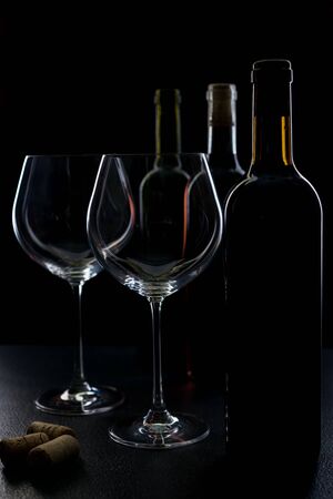 glass of red and pink wine on a black background. Wine list menu. Close up of the power of glasses and bottles in low keyの写真素材