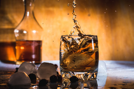 Splash of cold ice in glass of whiskey isolated on a light backgroundの写真素材