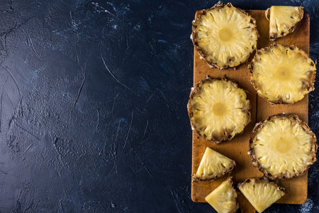 Pineapple on wood texture background. Whole and sliced ??tropical pineapple on a wooden board. Top...