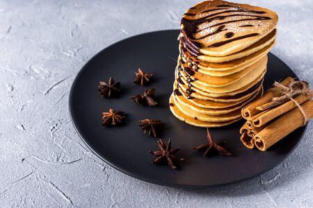 Fresh sweet pancakes with chocolate jam, cinnamon sticks and marshmallows on a gray background with place for your textの写真素材